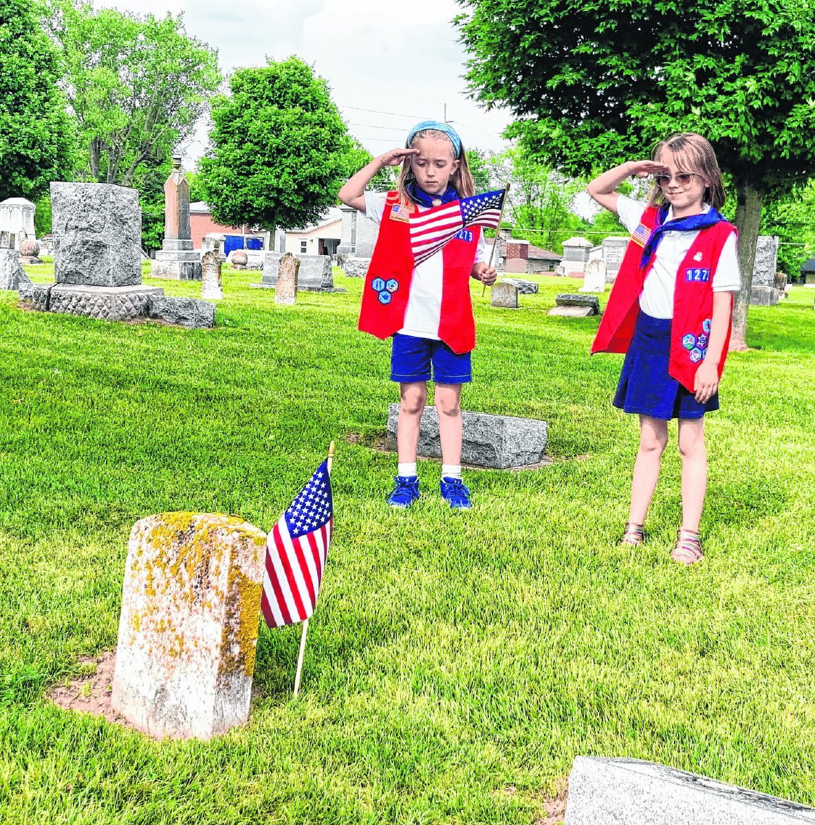 Adalynn Schile, left, and Elizabeth Scheiderer salute the grave of a Civil War veteran at Immanuel Lutheran Cemetery in Seymour.  Mitchell Banks | the tribune